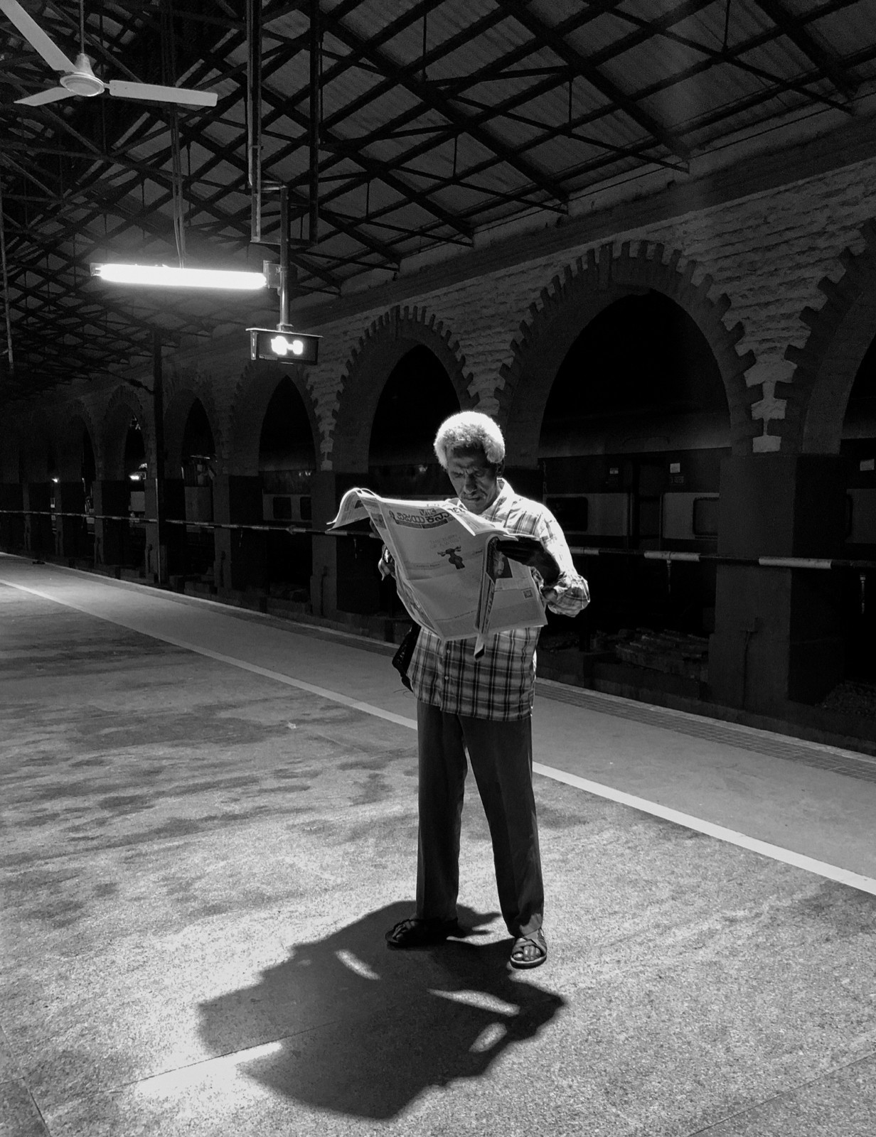 Reading a newspaper on the station platform.