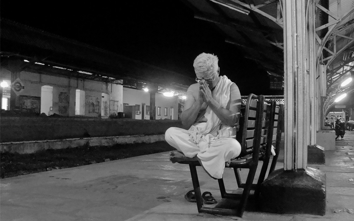 Man praying on a railway platform.
